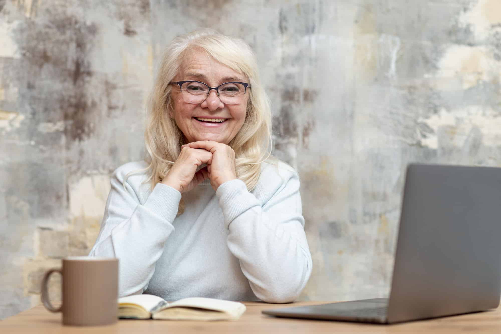 older women with glasses needs cataract surgery in front of a computer